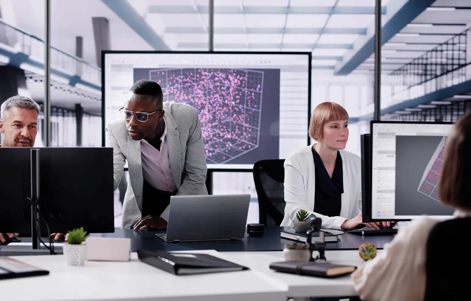 Team of professionals collaborating in a modern office with large digital screen.