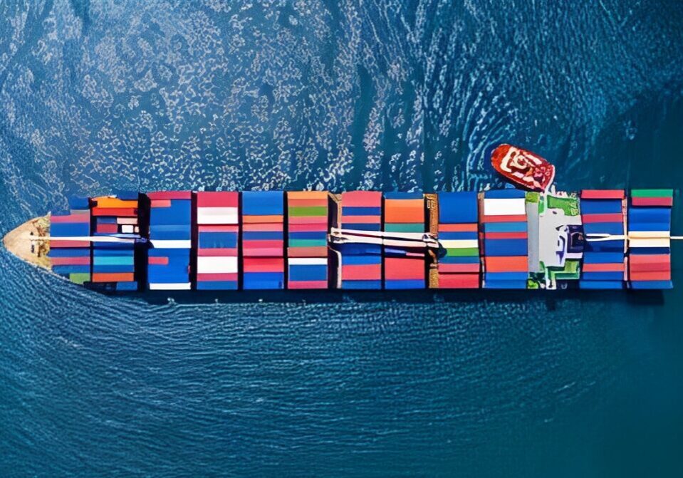 Aerial view of a container ship with colorful cargo containers, traveling through blue water.